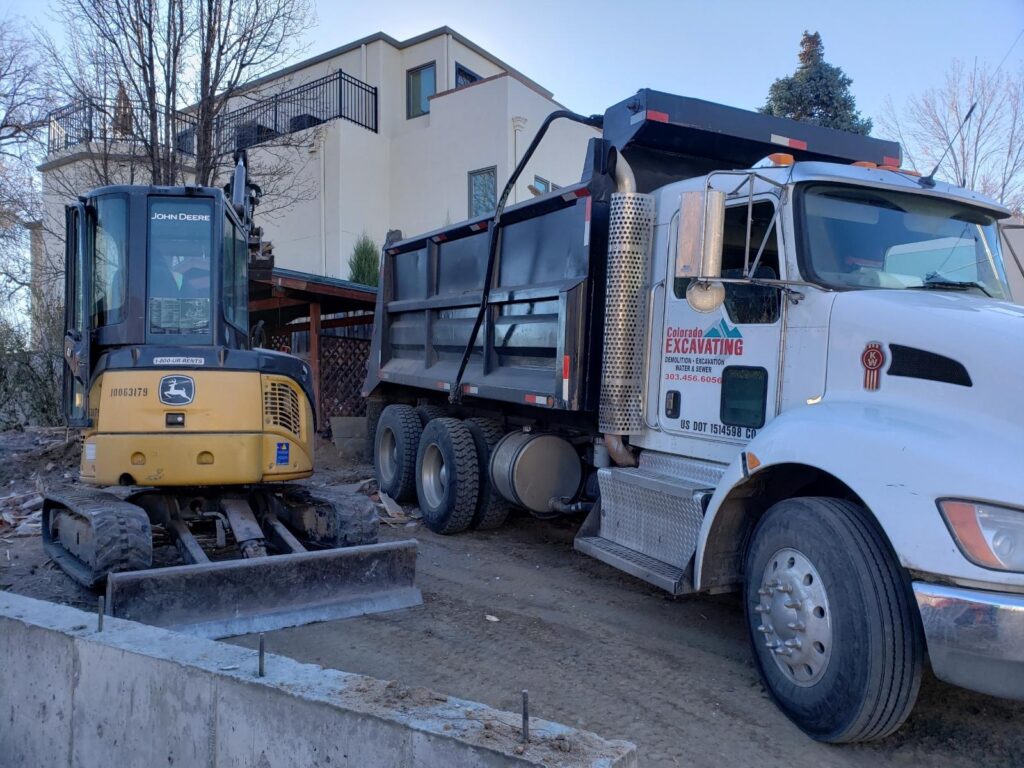 excavating companies near me? CO Excavation is a company with a mini excavator and dump truck at a residential job site.